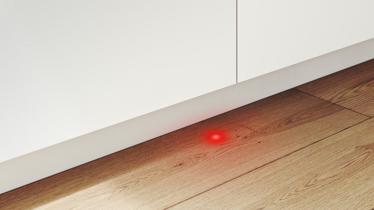 Ein rotes Licht leuchtet auf dem Boden in der Nähe einer weißen Wand.