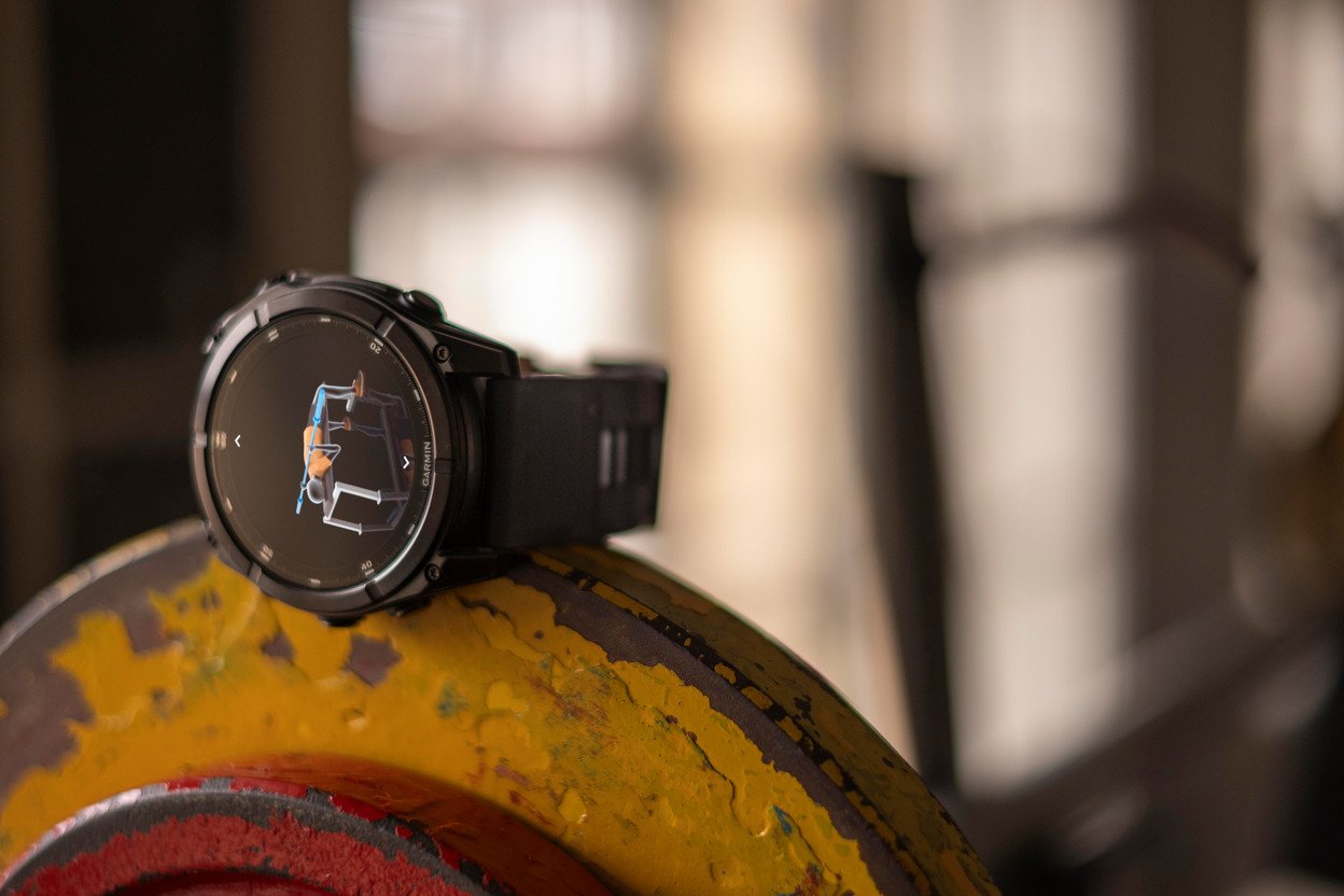 Schwarze Smartwatch auf einem Gewicht, zeigt Trainings-Oberfläche, mit verschwommenem Hintergrund.